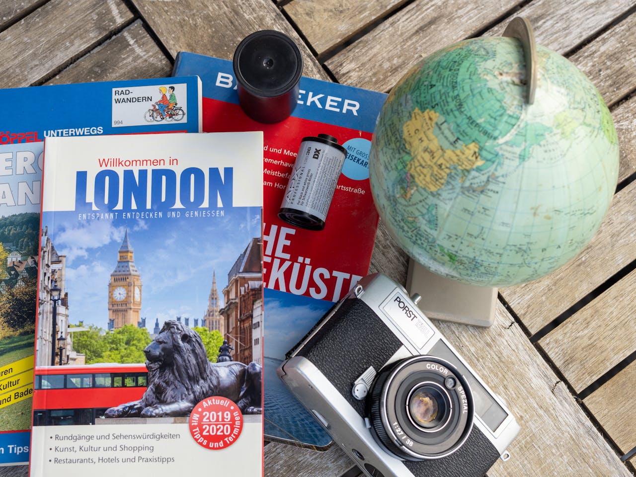 Flat lay featuring London travel guide, vintage camera, and globe, ideal for travel theme.