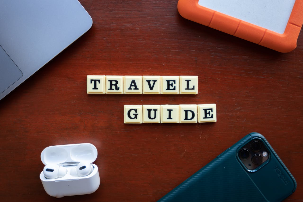 Flat lay of travel guide concept with smartphone, laptop, and headphones.